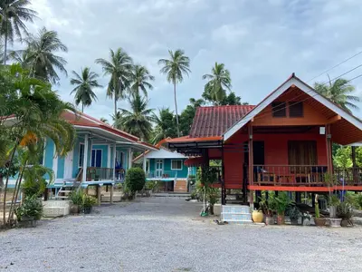 a row of houses with palm trees in the background at Patcharin Homestay in Ban Lo Pla Lai (1)