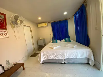 a bedroom with a bed with blue curtains and a fan at Patcharin Homestay in Ban Lo Pla Lai (1)