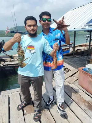two men holding a star fish on a boat at Patcharin Homestay in Ban Lo Pla Lai (1)