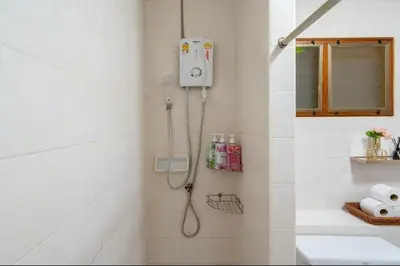 a shower in a white tiled bathroom with a sink at Solene Home Patong in Patong Beach