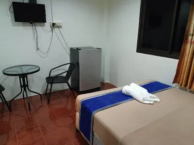 a bedroom with a bed and a table and a chair at Kata S.T House 2 in Phuket Town
