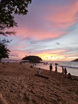 a group of people on a beach at sunset at Bohemian apartment at Ya Nui beach in Phuket Town