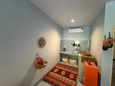 a small kitchen with an orange refrigerator and a rug at Bohemian apartment at Ya Nui beach in Phuket Town