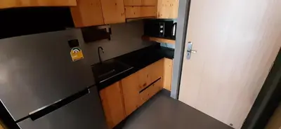 a small kitchen with a refrigerator and wooden cabinets at Relife The Windy in Phuket Town