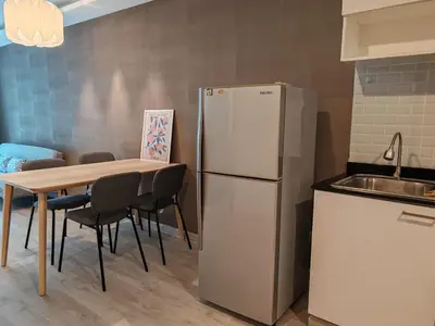 a kitchen with a refrigerator and a table with chairs at The Title Rawai Beach front 2BD in Rawai Beach
