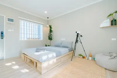 a white bedroom with a bed and a tripod at Dokdin's Family in Patong Beach