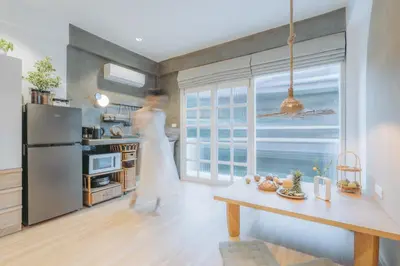 a woman is standing in a kitchen with a window at Dokdin's Family in Patong Beach