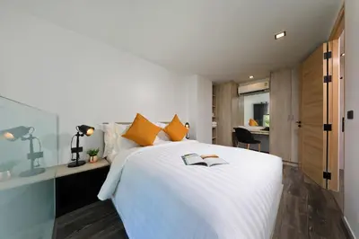 a bedroom with a large white bed with orange pillows at Utopia Naiharn in Nai Harn Beach
