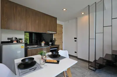 a kitchen with a white table and a white counter top at Utopia Naiharn in Nai Harn Beach