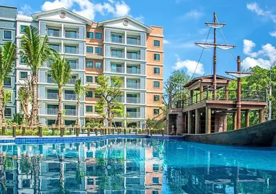 a swimming pool in front of a large building at TITLE NaiYang apartment-300m from sea in Phuket Town