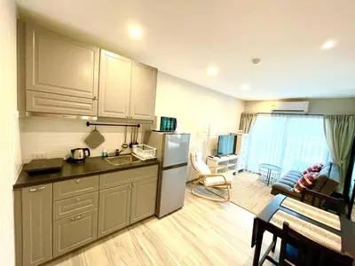 a kitchen with a refrigerator and a living room at TITLE NaiYang apartment-300m from sea in Phuket Town