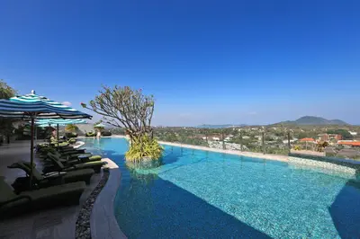 a large swimming pool with chairs and an umbrella at Calypso Garden by Holy Cow, 1-BR, private terrace in Rawai Beach