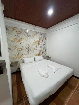 a white bed in a room with a marble wall at Relax Guest House in Patong Beach