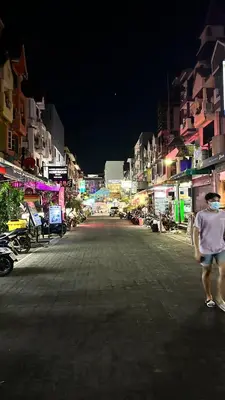 a man walking down a street at night at Relax Guest House in Patong Beach