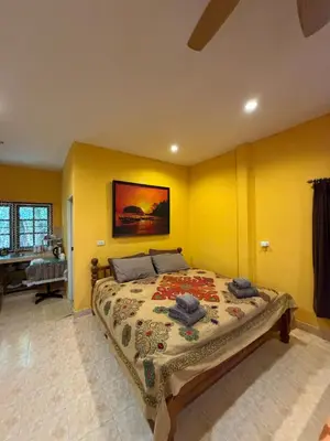 a bedroom with a bed with yellow walls and a piano at Good vibes bungalow at Ya Nui beach in Phuket Town