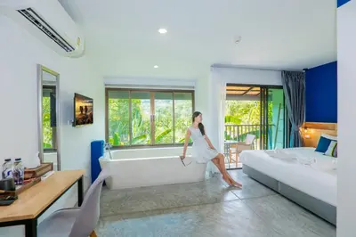 a woman walking in a living room with a tub at Kraam Silhouette Hotel and Cafe Phuket- Chalong pier Hotel in Chalong