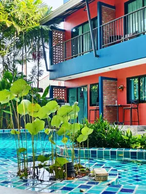 a swimming pool with plants in front of a house at Kraam Silhouette Hotel and Cafe Phuket- Chalong pier Hotel in Chalong
