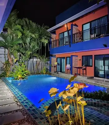 a swimming pool with chairs and umbrellas in front of a building at Kraam Silhouette Hotel and Cafe Phuket- Chalong pier Hotel in Chalong