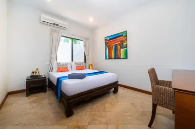 a bedroom with a bed and a desk and a window at Sanook dream villas Nai Harn Beach in Rawai Beach