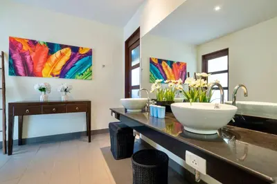 a bathroom with two sinks and a large painting on the wall at Sanook dream villas Nai Harn Beach in Rawai Beach