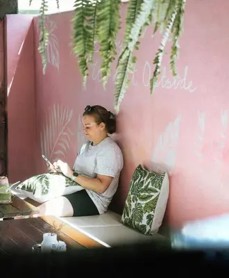 a woman sitting on a bench writing on a notebook at Twenty Two House in Patong Beach