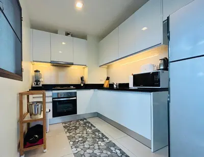 a kitchen with white cabinets and black appliances at Нескучный таунхаус в Лагуне in Phuket Town