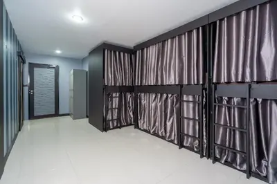 a corridor with curtains in a room with white tiles at Black Pantera Hostel in Patong Beach