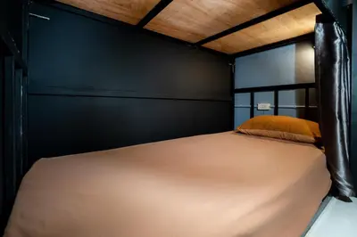 a bed in a bedroom with a black wall at Black Pantera Hostel in Patong Beach