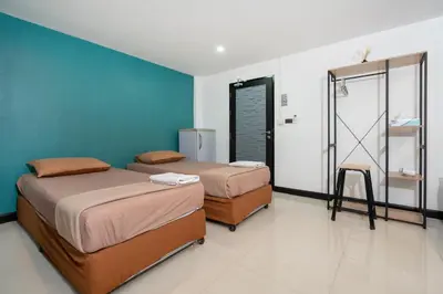 a room with two beds and a blue wall at Black Pantera Hostel in Patong Beach