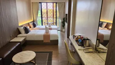 a hotel room with two beds and a table and a couch at Alaita Boutique Phuket in Ban Bo Rae