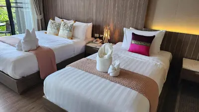 a hotel room with two beds with white and pink pillows at Alaita Boutique Phuket in Ban Bo Rae