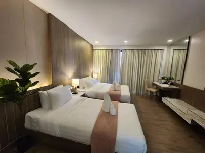 a hotel room with two beds and a desk at Alaita Boutique Phuket in Ban Bo Rae