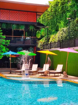a swimming pool with umbrellas and chairs and a fountain at Alaita Boutique Phuket in Ban Bo Rae