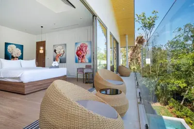 a bedroom with a bed and two wicker chairs at Himmapana Villas - Hills in Kamala Beach