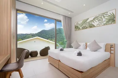 two beds in a room with a large window at Himmapana Villas - Hills in Kamala Beach