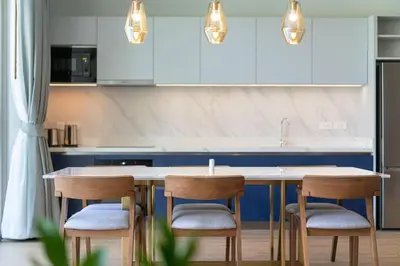 a kitchen with white cabinets and a table with chairs at Himmapana Villas - Hills in Kamala Beach