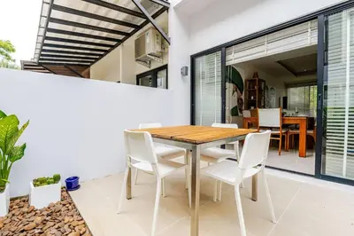 a dining room with a wooden table and white chairs at LP 65-57 Spacious holiday home close to the beach in Phuket Town