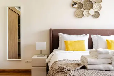 a bedroom with a bed with yellow pillows and a mirror at LP 65-57 Spacious holiday home close to the beach in Phuket Town