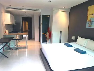 a bedroom with a large white bed and a kitchen at Emerald Terrace Condo 3-Studio Garden Gem in Patong Beach