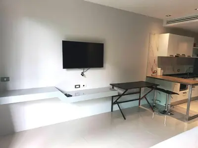 a living room with a table and a television on a wall at Emerald Terrace Condo 3-Studio Garden Gem in Patong Beach