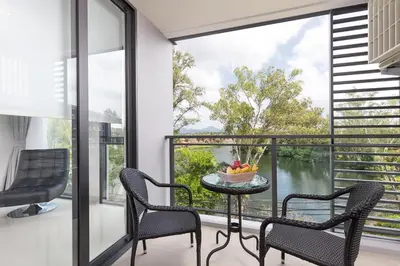 a balcony with chairs and a table with a bowl of fruit on it at Cassia Residence Laguna Phuket Holiday Rental Apartment, Bang Tao Beach in Phuket Town