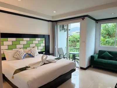 a bedroom with a bed and a green chair at COZY Residence Patong in Patong Beach