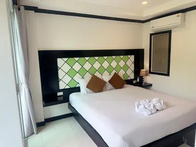 a bedroom with a white bed with a black headboard at COZY Residence Patong in Patong Beach