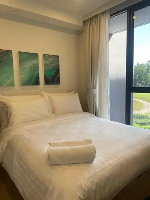 a bedroom with a large white bed with a window at Modern Golf course view Apartment in Sky Park Laguna in Phuket Town