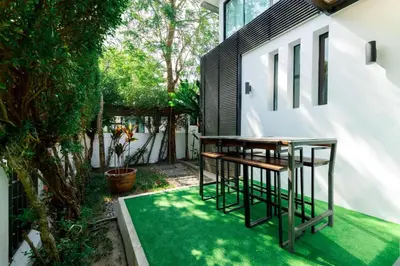 a patio with two stools on a green lawn at Kamala family friendly pool villa by Lofty in Kamala Beach