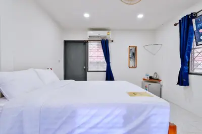 a bedroom with a large white bed with blue curtains at GP House Krabi Aonang Beach in Ao Nang Beach