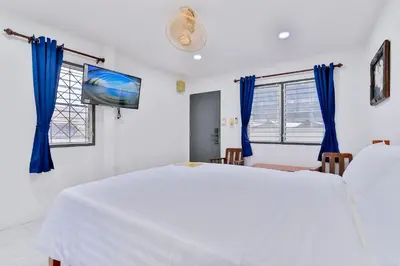 a bedroom with a white bed and a flat screen tv at GP House Krabi Aonang Beach in Ao Nang Beach