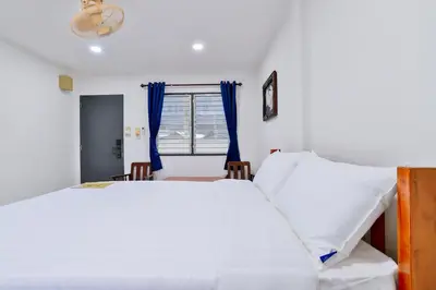 a bedroom with a large white bed and blue curtains at GP House Krabi Aonang Beach in Ao Nang Beach