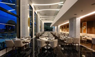 a dining room with tables and chairs and windows at Luxury sea view apartment at Mida Grande in Surin Beach