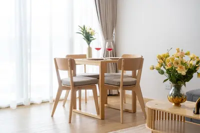 a dining room table with four chairs and a vase of flowers at Laguna Beachside 1 bedroom apartment 2 minutes from the beach in Phuket Town